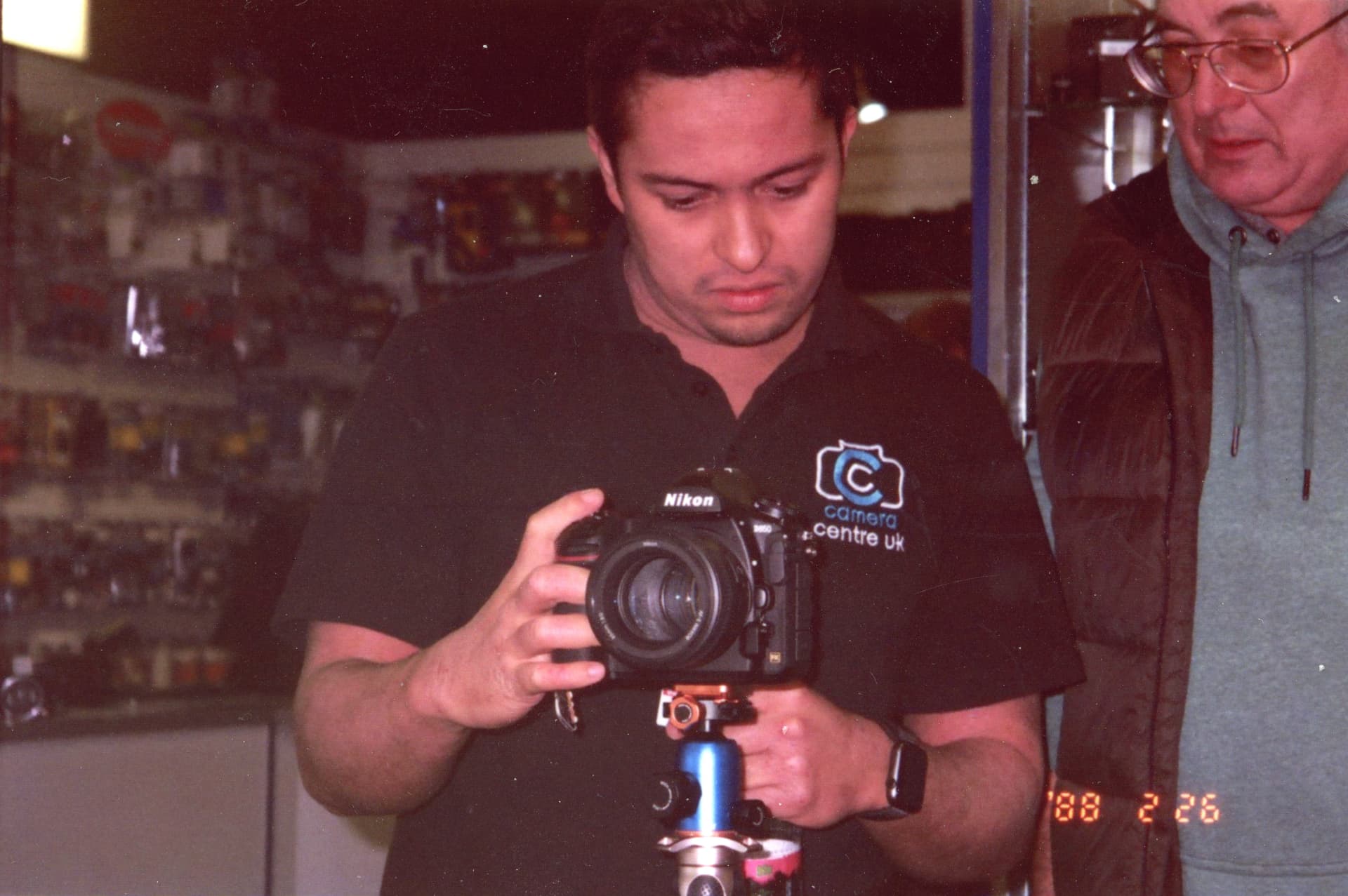 Camera Centre UK staff member showing a customer how his Nikon DSLR works on a tripod in store