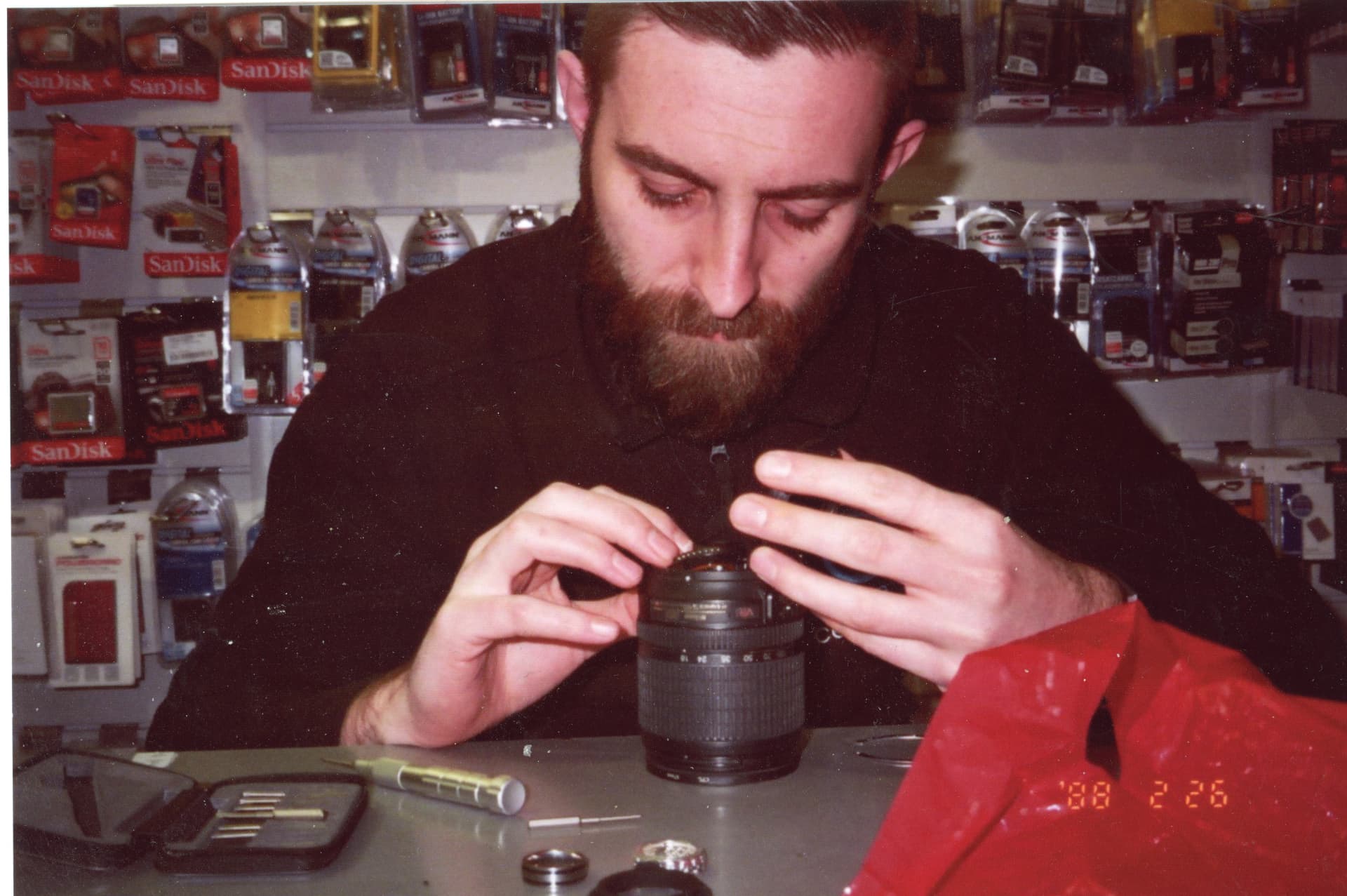 Bill at the Camera Centre UK counter carefully repairing a zoom lens with a screwdriver set laid out