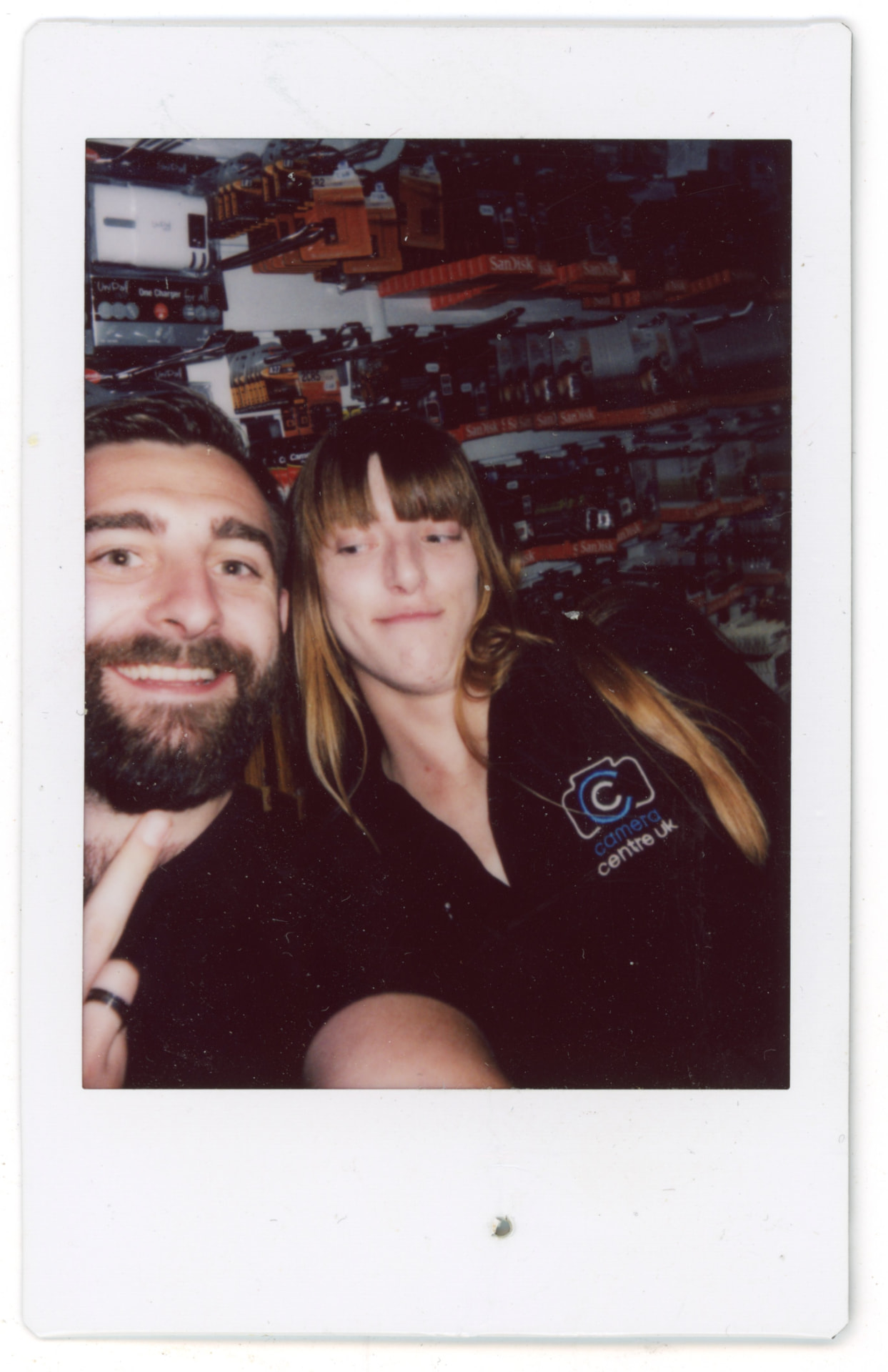 Instax photo of Bill and Tash together in the Camera Centre UK shop, shelves of accessories behind them